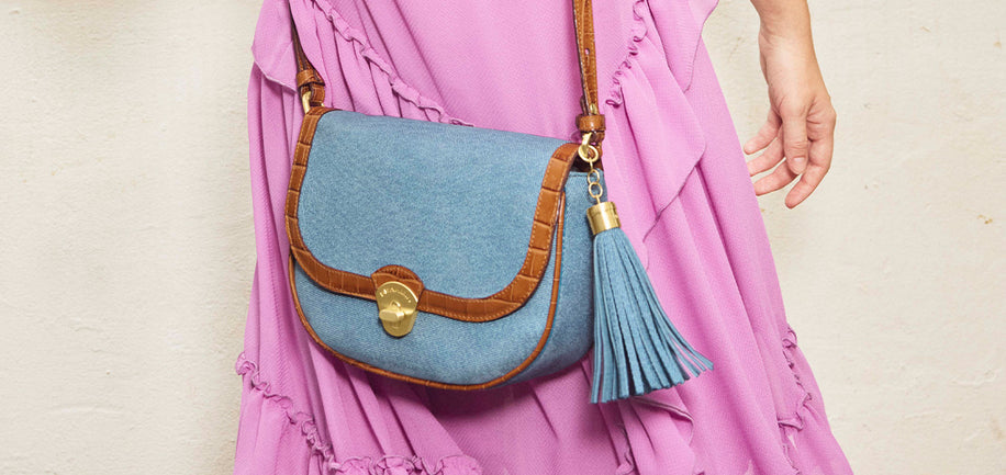 Denim portia handbag with a tassel held by a person wearing a pink dress.