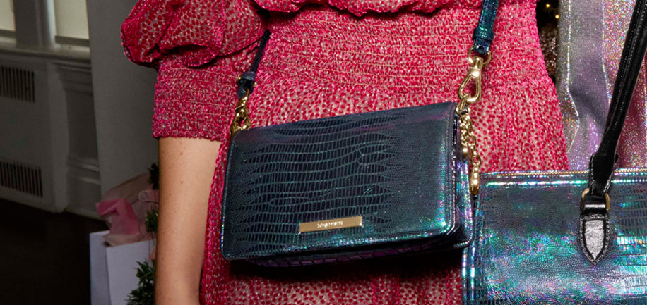 Person wearing a red textured outfit with a colorful Minuette crossbody and Sophia satchel with a reflective surface