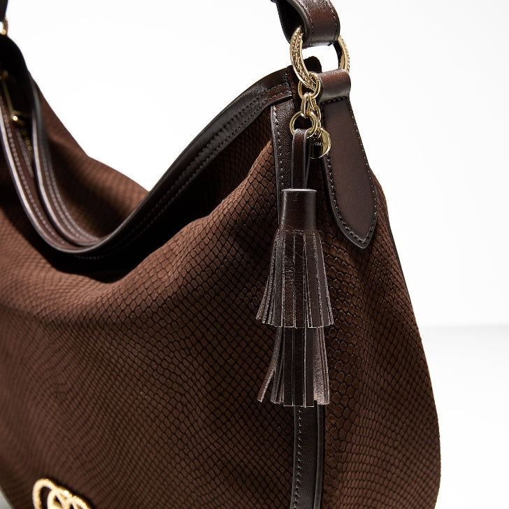 Detail shot of a brown textured-leather hobo with a double-layer leather tassel and gold ring hardware at the strap