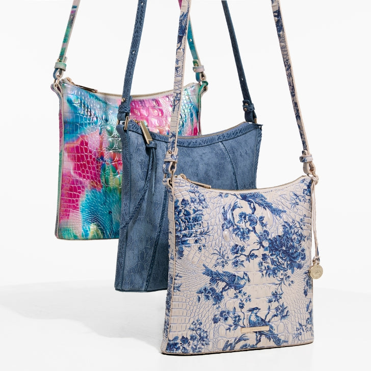 Brahmin Katie crossbody handbags showcased in vibrant floral print, denim blue, and elegant blue and white floral patterns with crocodile-textured finishes.